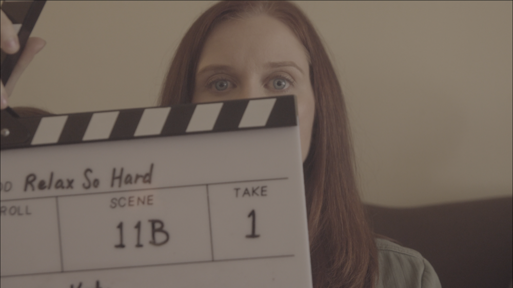 Kate peers over a film slate clapper board